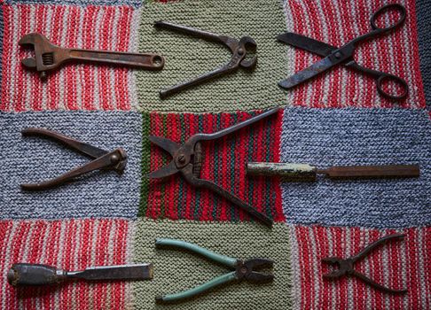 Still life with old and rusty tools on a multi-colored knitted tablecloth flatlay