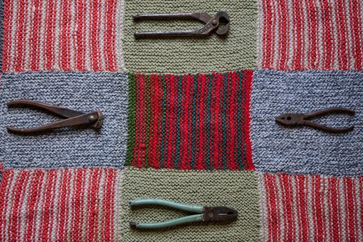 Still life with old and rusty tools on a multi-colored knitted tablecloth flatlay