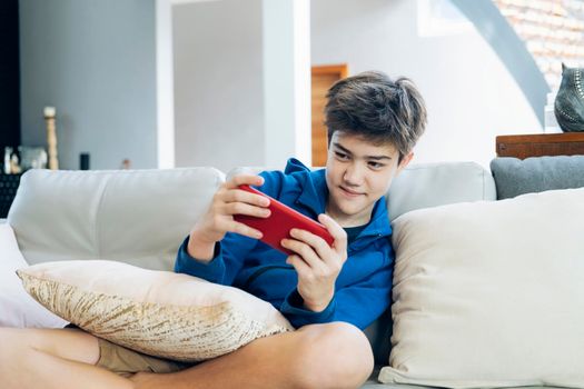 The boy playing online game on smartphone at home.
