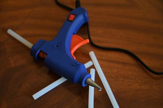 a glue gun with glue rods is lying on the table close-up