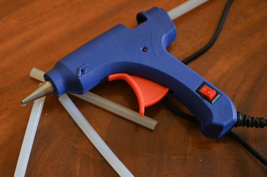 a glue gun with glue rods is lying on the table close-up