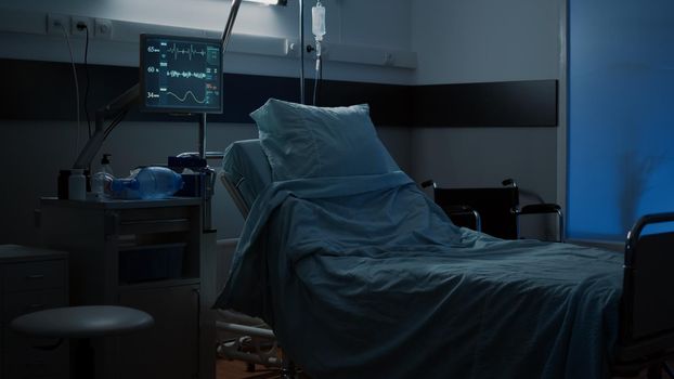 Modern hospital ward with comfortable empty bed used for medical treatment. Nobody in facility room with clinical equipment, monitor, computer, wheelchair, medicine, healing technology