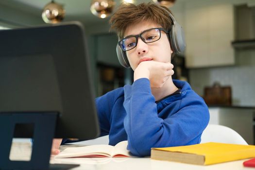 Distance learning online education. A schoolboy boy studies at home and does school homework. A home distance learning.