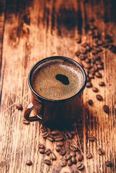 Brewed black coffee in metal mug over wooden surface