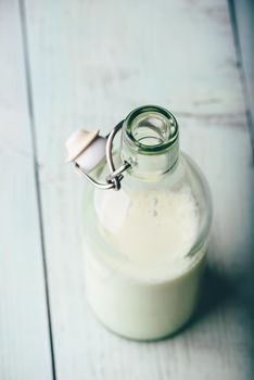 Milk in glass bottle on wooden surface. High angle view