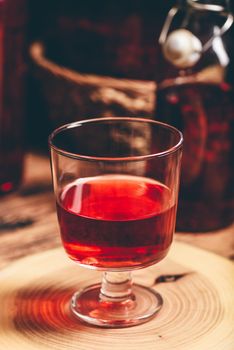 Homemade berry wine in glass on wooden surface