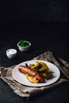 Oven baked pork sausage with green bell peppers, onion and herbs on white plate
