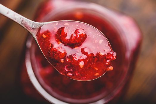 Spoonful of homemade raspberry jam over jar