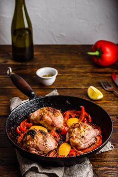 Chicken thighs baked with red bell peppers, rosemary and lemon in cast iron skillet.