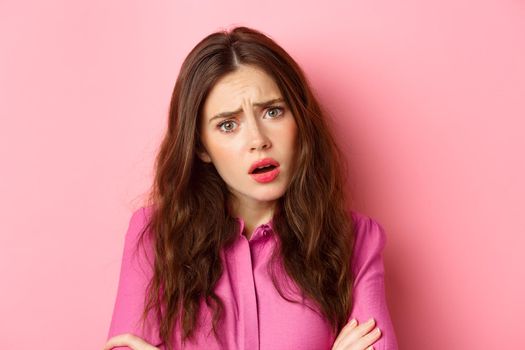 Close up portrait of sad young woman hear upsetting store, look with pity and compassion, standing over pink background.
