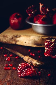 Pomegranate fruits with knife on rustic wooden table