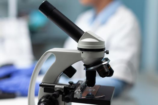 Selective focus on medical microscope standing on table in biochemistry hospital laboratory. Specialist doctor typing medicine expertise working at microbiology experiment. Microscope glass sample