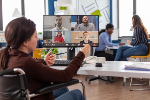 Handicapped paralyzed invalid employee during virtual meeting talking on videocall working from start up business office discussing with partners online using webcam. Businesswoman on video conference.