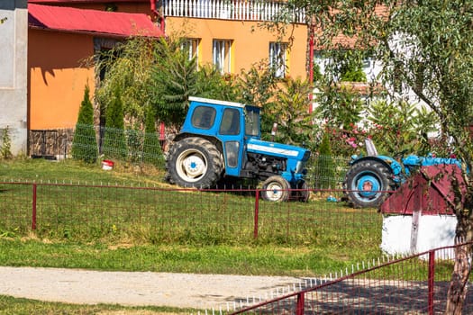 Old blue vintage tractor in fron of farm land in Viscri Village, Romania