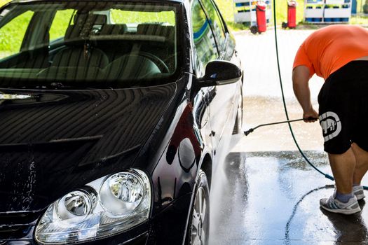 Washing and cleaning car in self service car wash station. Car washing using high pressure water in Bucharest, Romania, 2021