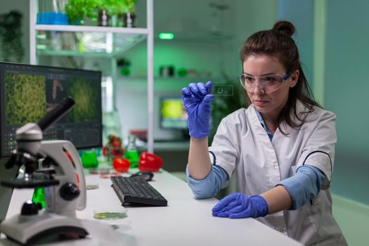 Chemist scientist looking at green leaf sample checking genetic mutation for biological experiment. Scientist analyzing organic gmo plants while working in microbiology laboratory.