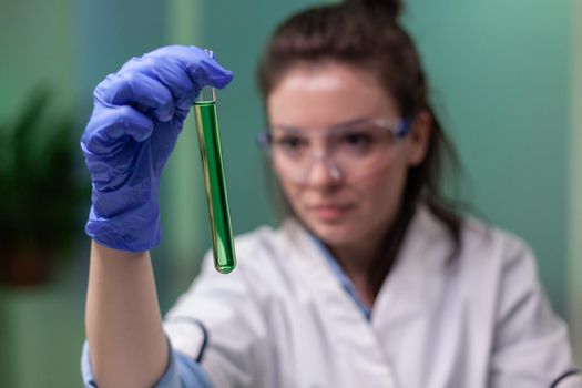 Closeup of scientist woman looking at test tube with dna sample examining for microbiology experiment. Researcher biologist working in agriculture laboratory developing gmo expertise on plants.