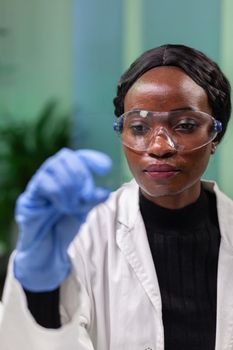 Botanist researcher scientist analyzing green liquid sample under microscope for microbiology experiment. Chemist specialist discovering organic gmo plants while working in pharmaceutical laboratory.