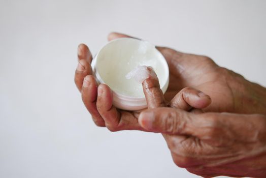 senior woman using petroleum jelly onto skin at home close up.