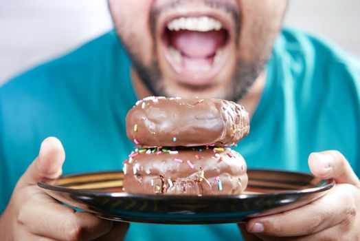 young man open his mouth eating donut , selective focus