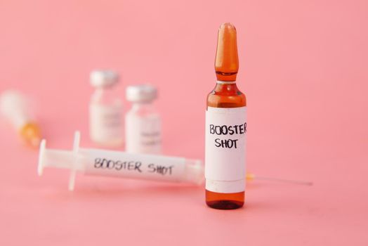 booster shot dose coronavirus vaccine and syringe on pink .