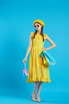 cheerful woman yellow dress shopping fun blue background. High quality photo