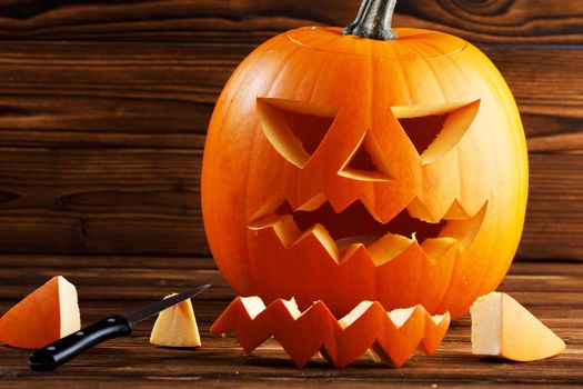 Carving of Halloween pumpkin in progress, knife on wooden background