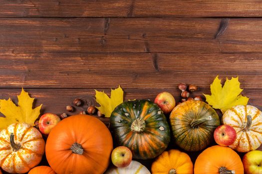 Fall border with pumpkins, leaves and apples. Top view on a rustic dark wood background with copy space for text