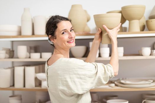 Ceramist woman holding a potter in her studio