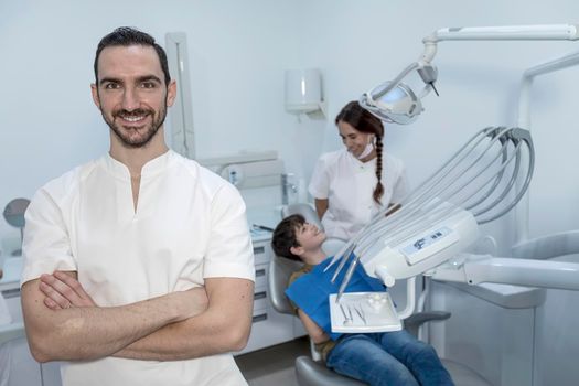 Portrait of a dentist with his team working in the background