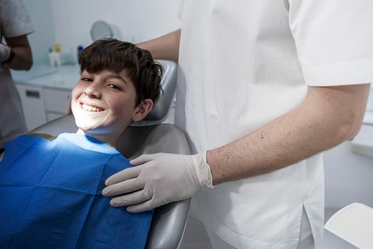 A cute boy is being examined by a professional pediatric dentist. Very happy boy after the visiting of doctor at the clinic with beautiful white smiles. Copy space.