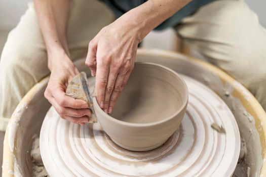 Closeup woman hands making clay pot in workshop. Unrecognized artist sculpting from wet clay in studio. Unknown female ceramist doing handmade product in pottery