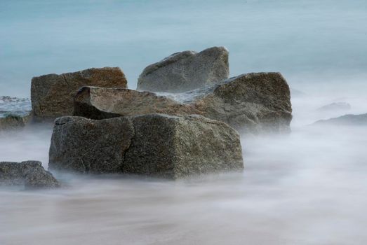 Long Exposure Sunrise Seascape with running waves on the rocks at the beach