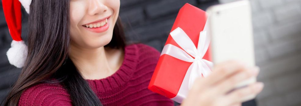 Closeup young asian woman selfie video call online with friends and show gift box in Christmas day on phone at home, social distancing, new normal, female video conference, communication and holiday.