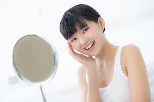 Beautiful face of young asian woman with happy smiling and touch cheek looking mirror with charming, makeup of beauty facial girl with skincare and cosmetic treatment, skin care and healthy concept.