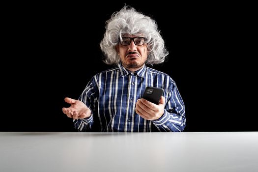 A bewildered senior, typical boomer, does not understand how to use the smartphone on black background