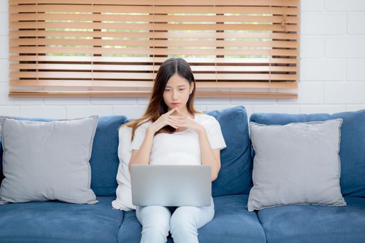Young asian woman work on laptop computer on sofa at home with frustrated and bored, freelance girl unhappy and tired with unsuccessful, upset from problem, failure and mistake, business concept.