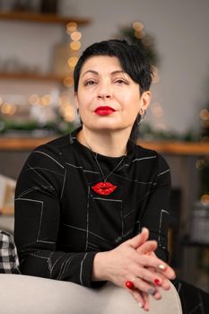 Portrait of a stylish tired adult woman, thinking about something while sitting on the couch.