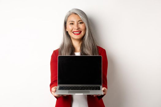 Business. Smiling asian businesswoman showing blank digital tablet screen, standing over white background.