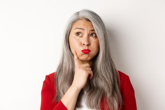 Covid, pandemic and business concept. Businesswoman in red blazer and face mask using hand sanitizer to clean and disinfect, standing over white background.