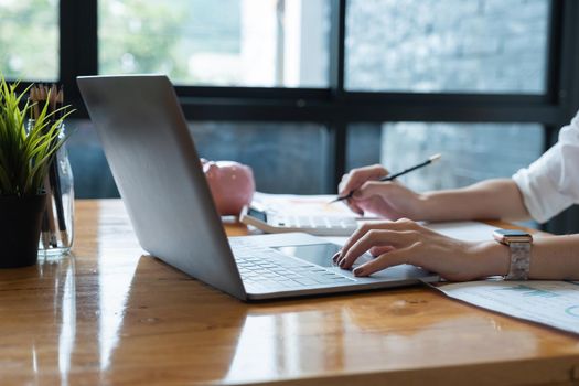 Business woman working in finance and accounting Analyze financial budget with calculator and laptop computer at home office.