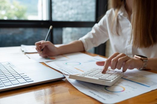 Business woman doing accounting with calculator and paperwork, financial adviser working.