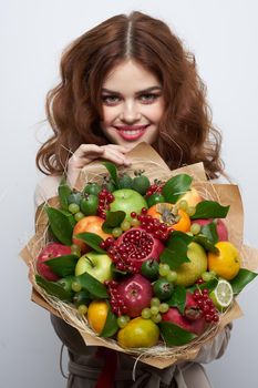 cheerful woman bright makeup attractive look a bouquet of fruits light background. High quality photo