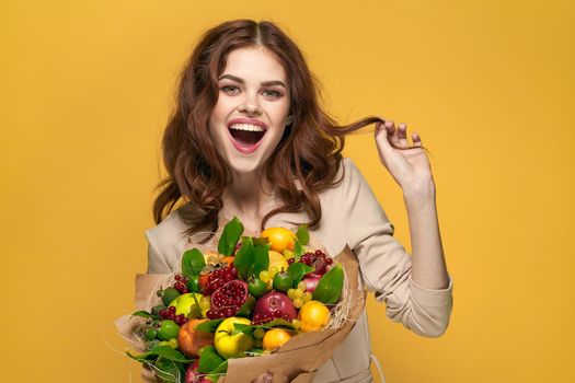pretty woman fun posing fruit bouquet vitamins yellow background. High quality photo