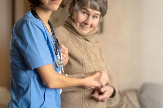 A young nurse shows care and professionalism in relation to an elderly woman, a pensioner. Young woman doctor visits the patient at home and conducts medical therapy