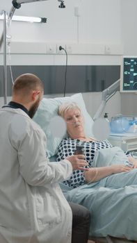 Doctor giving bottle of pills for old patient with illness for healthcare treatment and prescription medicine in hospital ward. Medic holding flask with medication for woman recovery