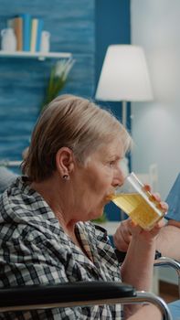 Medical assistant giving glass with effervescent vitamin to patient in wheelchair. Aged disabled woman holding drink with healthcare treatment for recovery. Adult receiving support