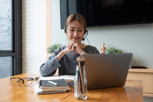 Cropped shot smiling asian woman freelancer wearing headset, communicating with client via video computer call. Millennial pleasant professional female tutor giving online language class.