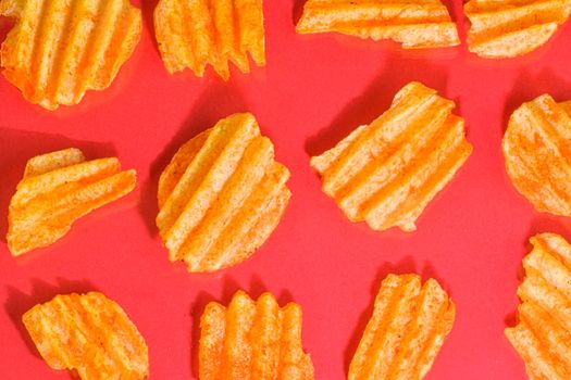 Ribbed potatoes snack with pepper on red background. Ridged potato chips on red background. Collection. Flat lay. Close-up.