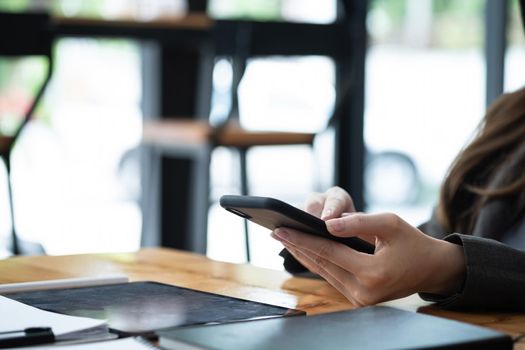 Close up woman using mobile phone on workplace.